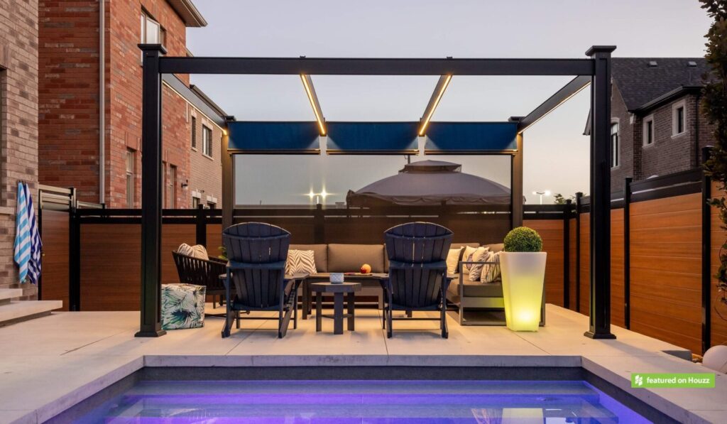 Modern outdoor patio with a pergola, comfortable seating, illuminated plant pot, and a small pool with blue lighting at dusk. Warm ambiance, no people.