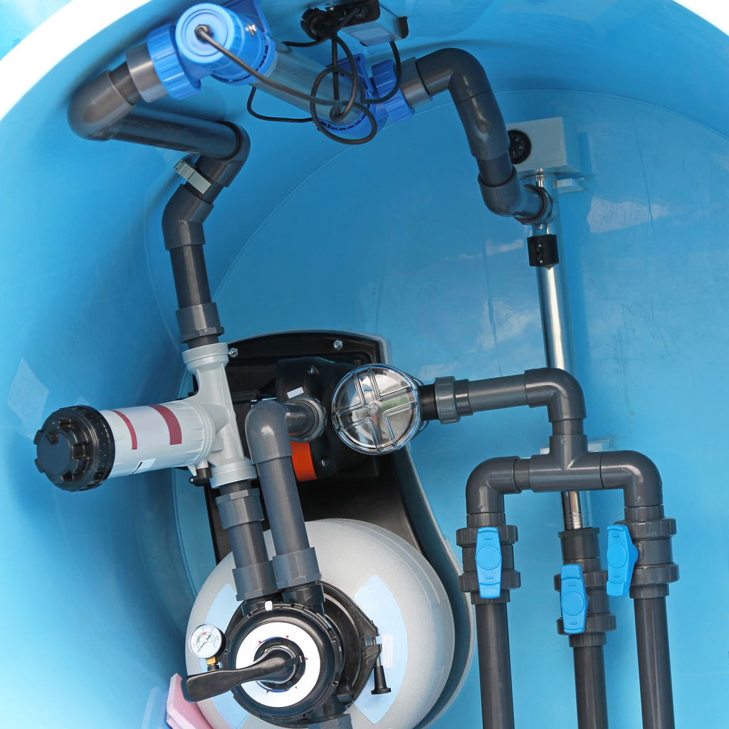 This image shows the intricate internal components of a machine, including pipes, gauges, and pumps within a blue casing, possibly part of a water system.