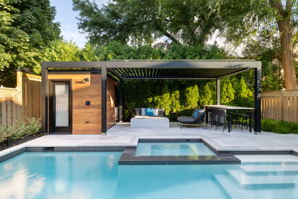 A modern backyard with a swimming pool, patio area, pergola, lounge chairs, dining furniture, outdoor cabin, and lush greenery surrounding the space.