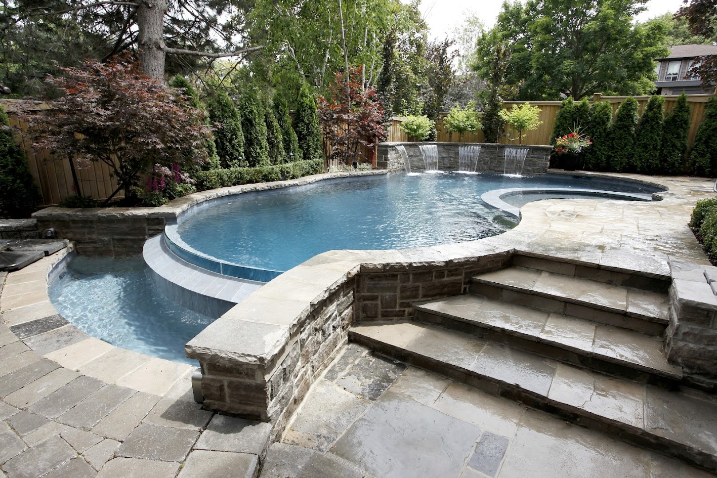A custom concrete pool with a negative edge and stone steps.