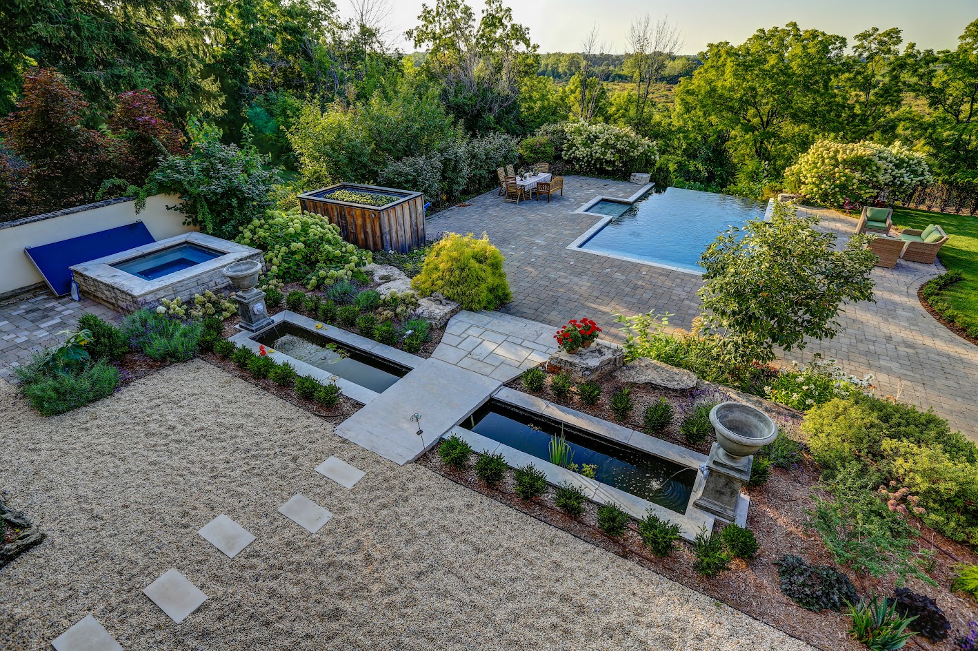 A custom pool and water feature in a backyard surrounded by lush greenery.